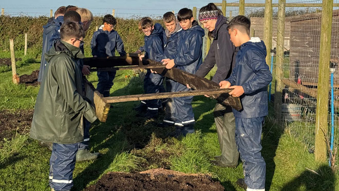 Young people on a school residential lifting a gardening frame together.